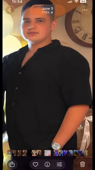 Man in black shirt posing indoors with a large wall clock