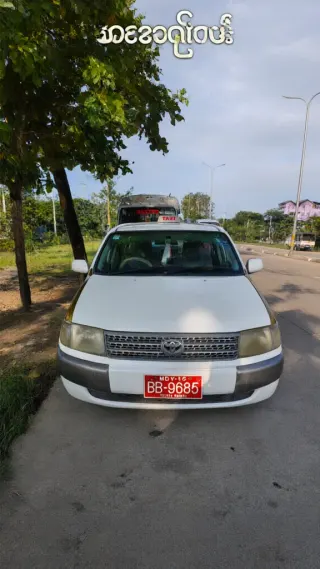 White Toyota taxi parked under a tree with Burmese text