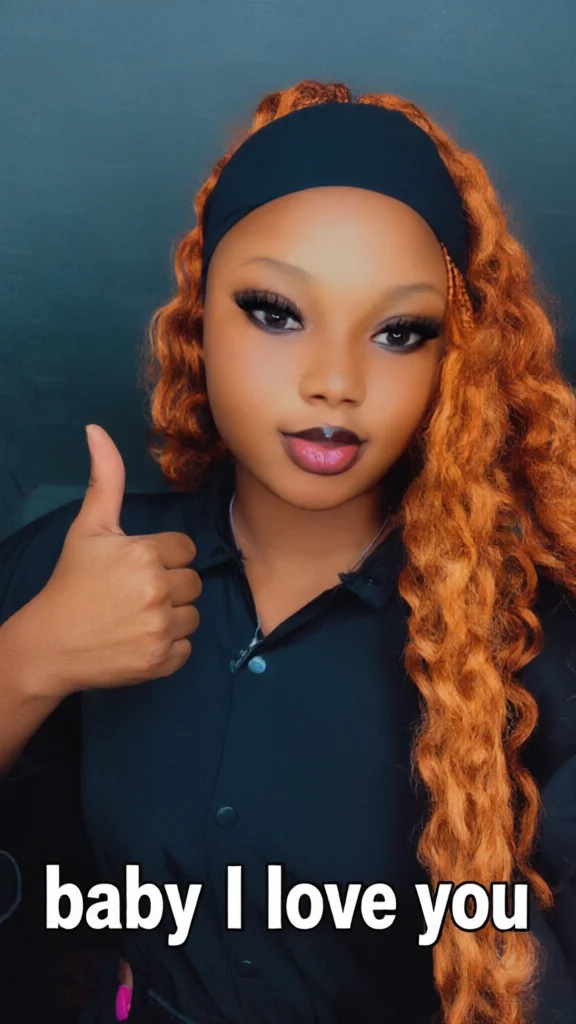 Individual with long wavy reddish hair and black headband poses with raised hand. White phrase at bottom expresses love.