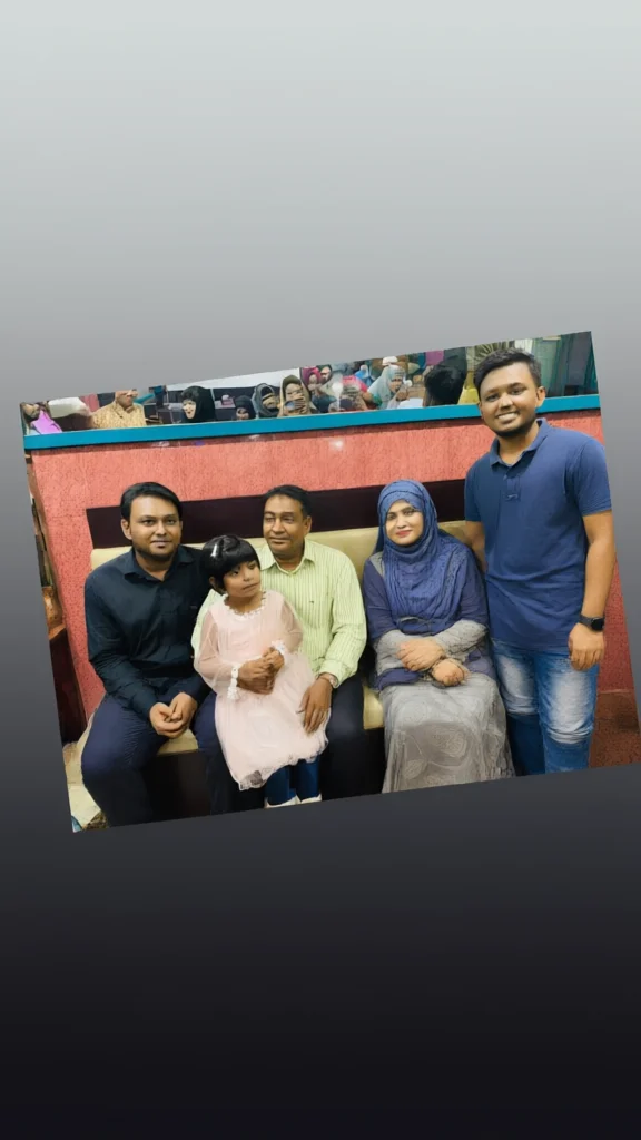 Family photo of five people sitting on a beige couch with a